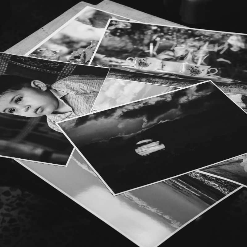 Kit com 20 fotos reveladas no tamanho 15x21, empilhadas de forma elegante ao lado de um Photo Box.
